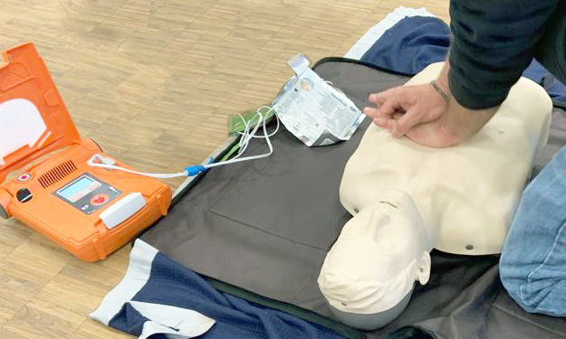 Un homme effectue un massage cardiaque sur un mannequin pour expliquer la procédure aux participants.